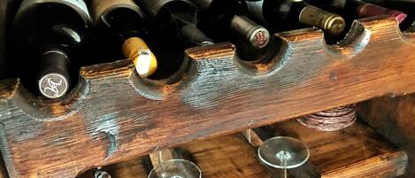 A wooden wine rack holding several wine bottles and glasses.