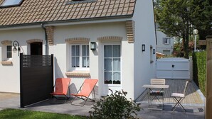 Et hus med tegltag, en overdækket terrasse med udendørs møbler og et lille haveområde.