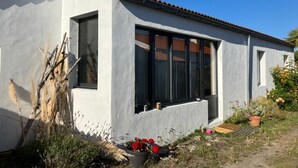 Une maison moderne avec une façade blanche, de grandes fenêtres et un toit recouvert de tuiles.