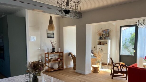 Un salon moderne avec un plancher en bois, une table à manger décorée de bougies, un fauteuil rouge et une bibliothèque.