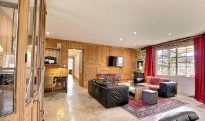 Relax in a spacious living area with a large flat-screen TV, comfortable seating, and a dining table.