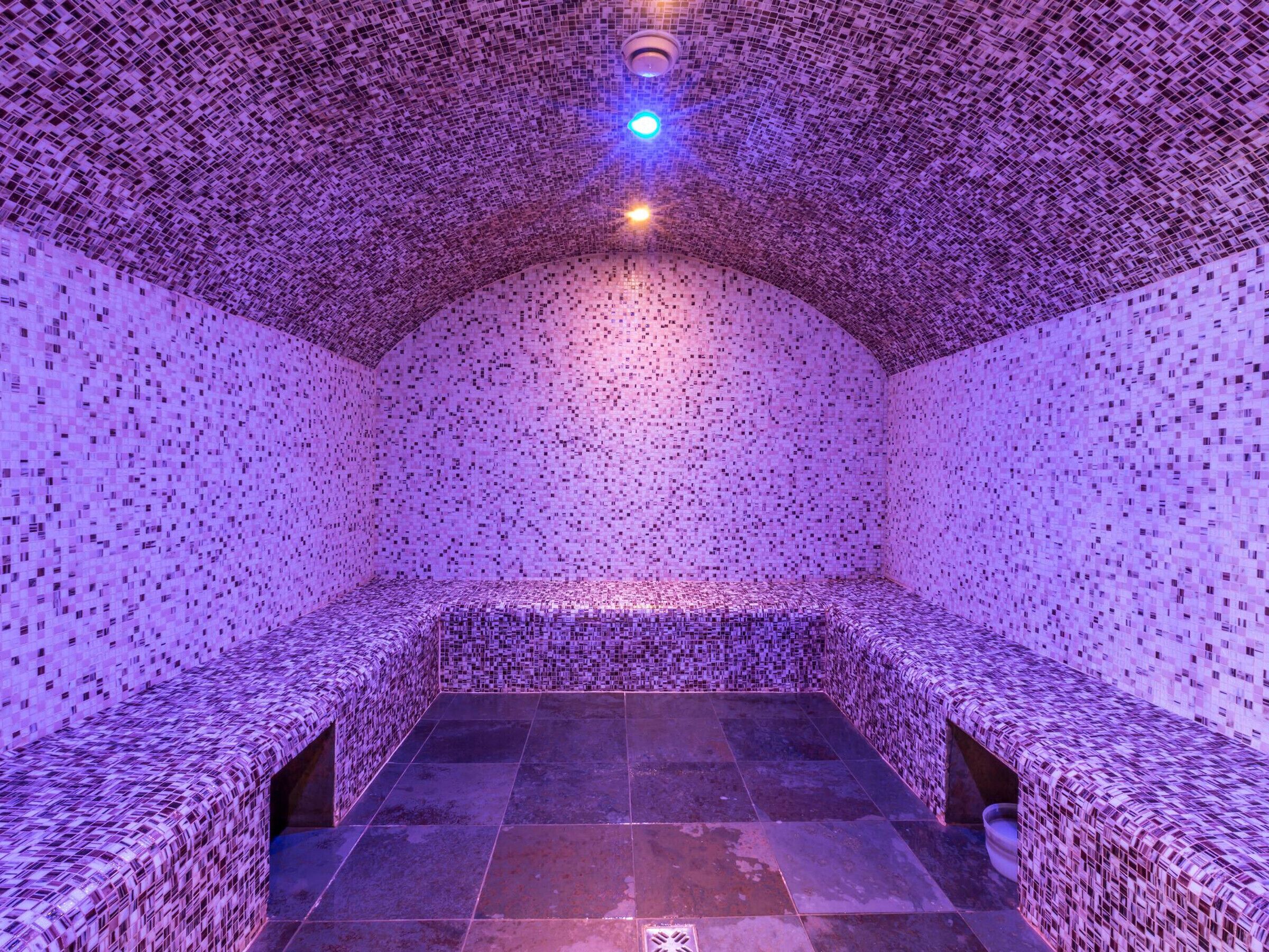 Una stanza con soffitto e pareti decorate da un motivo, un lampadario al centro e pavimento piastrellato.