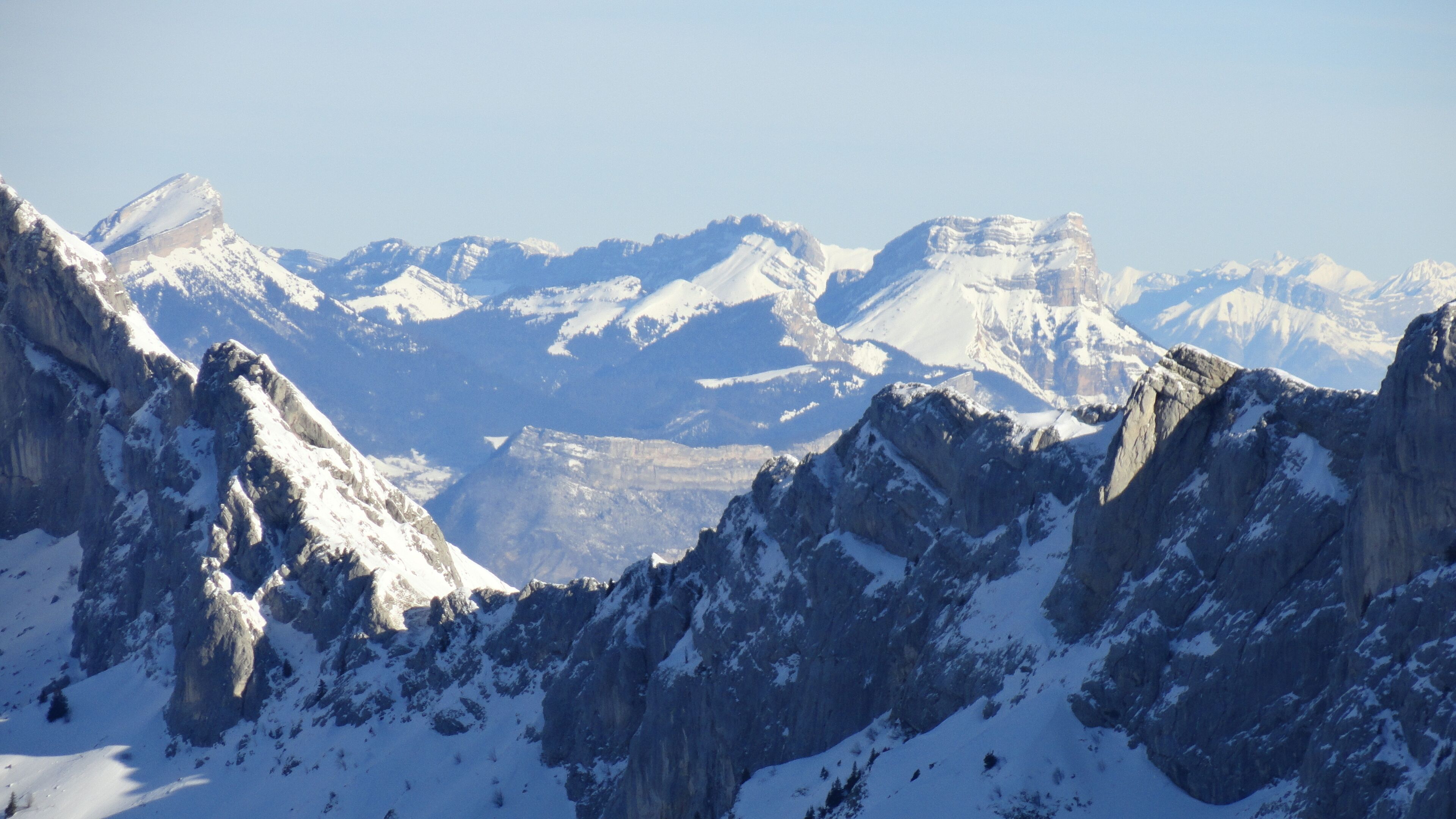 Paesaggio montuoso con cime innevate e terreno roccioso.