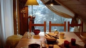 A cozy dining area with a wooden table set for two, featuring a vase with flowers, a bowl, and a candle holder. - 6 to 7 sleeps, spacious with central fireplace, wooden top of the chalet. (Villard-De-Lans)