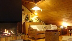 A cozy log cabin interior with a fireplace, wooden furniture, and a Christmas tree. - 6 to 7 sleeps, spacious with central fireplace, wooden top of the chalet. (Villard-De-Lans)