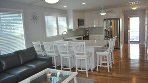 Una cocina moderna con armarios blancos, electrodomésticos de acero inoxidable y una isla central con taburetes.