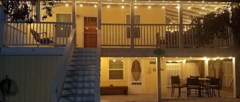 A two-story house with a covered porch, a staircase, and outdoor seating area.