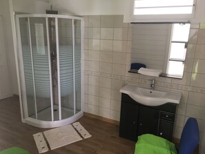 Ein Badezimmer mit Duschkabine, Waschbecken und Spiegel.