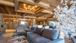Ein gemütliches Blockhaus-Interieur mit einer Eckcouch, einem Couchtisch mit Zeitschriften und einem Kamin.