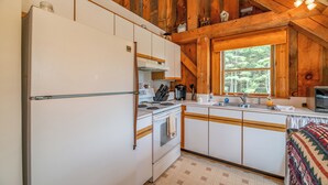 Une cuisine de taille réduite, avec des meubles blancs, une cuisinière et un évier.