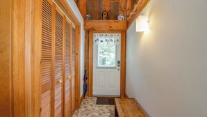 Un couloir en bois avec une porte blanche, un banc et une petite table.
