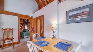 Un coin repas avec une table en bois, des chaises blanches et des sets de table bleus.
