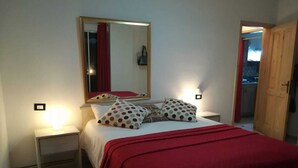 A bedroom with a bed, a bedside table, a nightstand, a mirror, and a door leading to a balcony. - Awesome Apartament , Sea View, Swimming pool, In Boca Chica Apt 29 (Boca Chica (santo Domingo))