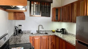 A kitchen with wooden cabinets, a stainless steel refrigerator, a stove, and a sink. - Villas Lambeau #1 Ocean View  - Fiber Optic / 1BR 1 BA (Uvita)