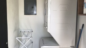 A laundry area with a washing machine, a drying rack, and a small cabinet. - Villas Lambeau #1 Ocean View  - Fiber Optic / 1BR 1 BA (Uvita)