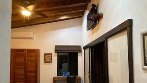 A small room with a bed, a desk with a chair, a window, and a door. - Villas Lambeau #1 Ocean View  - Fiber Optic / 1BR 1 BA (Uvita)