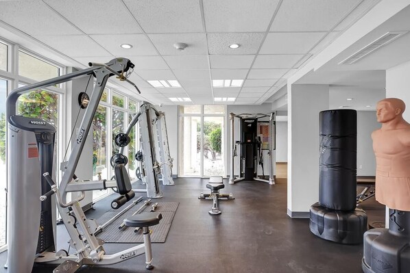 Un gimnasio con máquinas de cardio, equipo de levantamiento de pesas y un saco de boxeo.