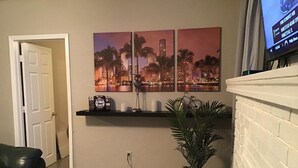 A living room with a black leather couch, a coffee table, a potted plant, a fireplace, and a wall-mounted TV. - Modern 3/1 house near Beaches and Midtown (Miami)