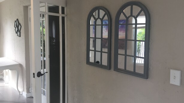 A hallway with a white door, a white table, and two arched windows with a view of the outside. - Modern 3/1 house near Beaches and Midtown (Miami)