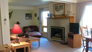 A living room with a fireplace, a television, a sofa, and a coffee table. - Mountain Condo For All Season Fun And Relaxation/ Family Friendly 2Bath2Bedrooms (Steamboat Springs)