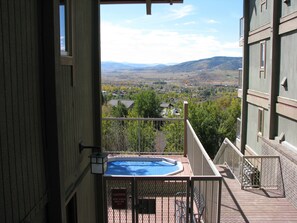 A balcony with a hot tub overlooking a residential area and distant mountains. - Mountain Condo For All Season Fun And Relaxation/ Family Friendly 2Bath2Bedrooms (Steamboat Springs)