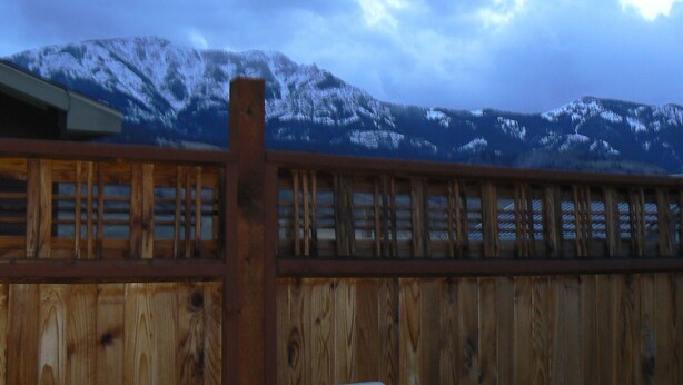 A wooden fence with a view of snow-covered mountains in the background.