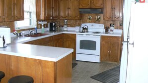 A kitchen with wooden cabinets, a white stove, and a sink.