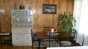 A dining area with a wooden table, chairs, a cabinet with glass doors, and a framed picture on the wall.