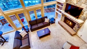 A spacious living room with a stone fireplace, large windows, and a comfortable seating area. - Spacious Home, 2 Living Areas, Jacuzzi Hot Tub, Mountain Views, & Close to Town! (Breckenridge)