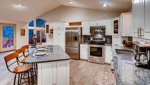 A modern kitchen with white cabinets, stainless steel appliances, and a large island. - Spacious Home, 2 Living Areas, Jacuzzi Hot Tub, Mountain Views, & Close to Town! (Breckenridge)