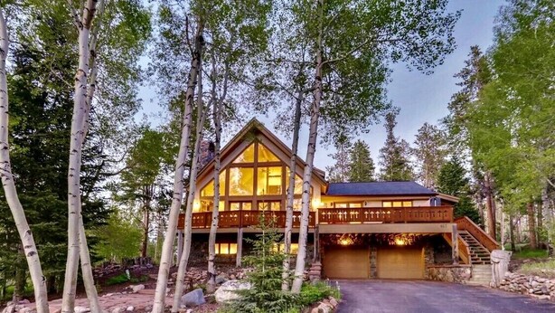A log cabin with a large deck, surrounded by trees. - Spacious Home, 2 Living Areas, Jacuzzi Hot Tub, Mountain Views, & Close to Town! (Breckenridge)