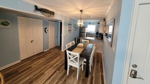 A spacious kitchen with a central island, wooden flooring, and a dining area with a table and chairs.