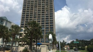 Un hotel moderno y alto con una serie de balcones, un cartel de dirección llamativo y una señal de calle que indica Ocean Blvd.