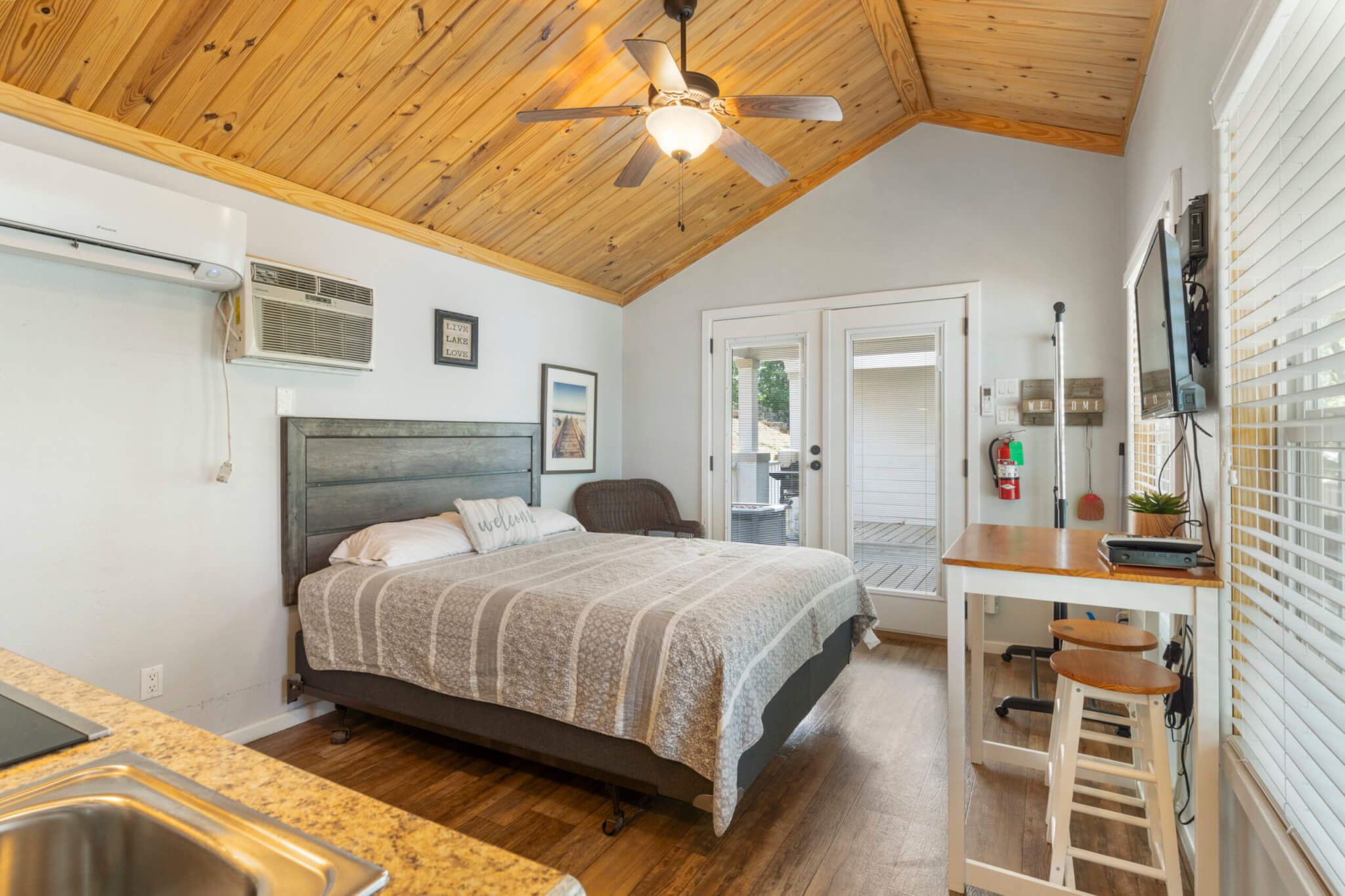 A bedroom with a bed, a desk, a chair, and a ceiling fan.
