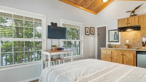 A compact room with a bed, a desk, a TV, and a kitchen area with wooden cabinets and a dishwasher. - Eagles Nest at CrossTimbers Marina (Sperry)
