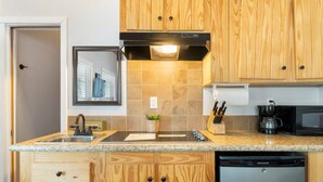 A kitchen with wooden cabinets, a granite countertop, a dishwasher, and a microwave. - Eagles Nest at CrossTimbers Marina (Sperry)