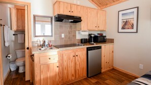 A compact kitchen with wooden cabinets, a dishwasher, and a microwave. - Eagles Nest at CrossTimbers Marina (Sperry)