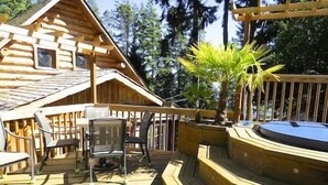 A wooden cabin with a deck, chairs, and a small pool.