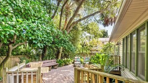 A wooden deck with a picnic table and chairs, surrounded by lush greenery and trees. - Great Family Beach House and 5% off weekly stays, last minute or mobile booking! (Folly Beach)