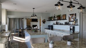 Cozinha moderna com bancadas de granito, uma ilha central com assentos e iluminação pendente.
