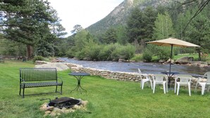 A riverside patio with a bench, chairs, and a table with an umbrella.