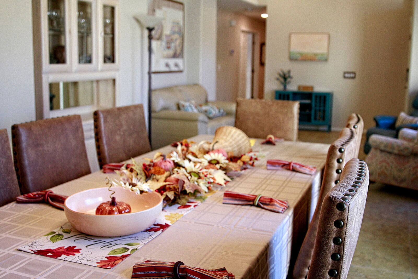 Une table à manger dressée avec un saladier, des fleurs et un set de table.