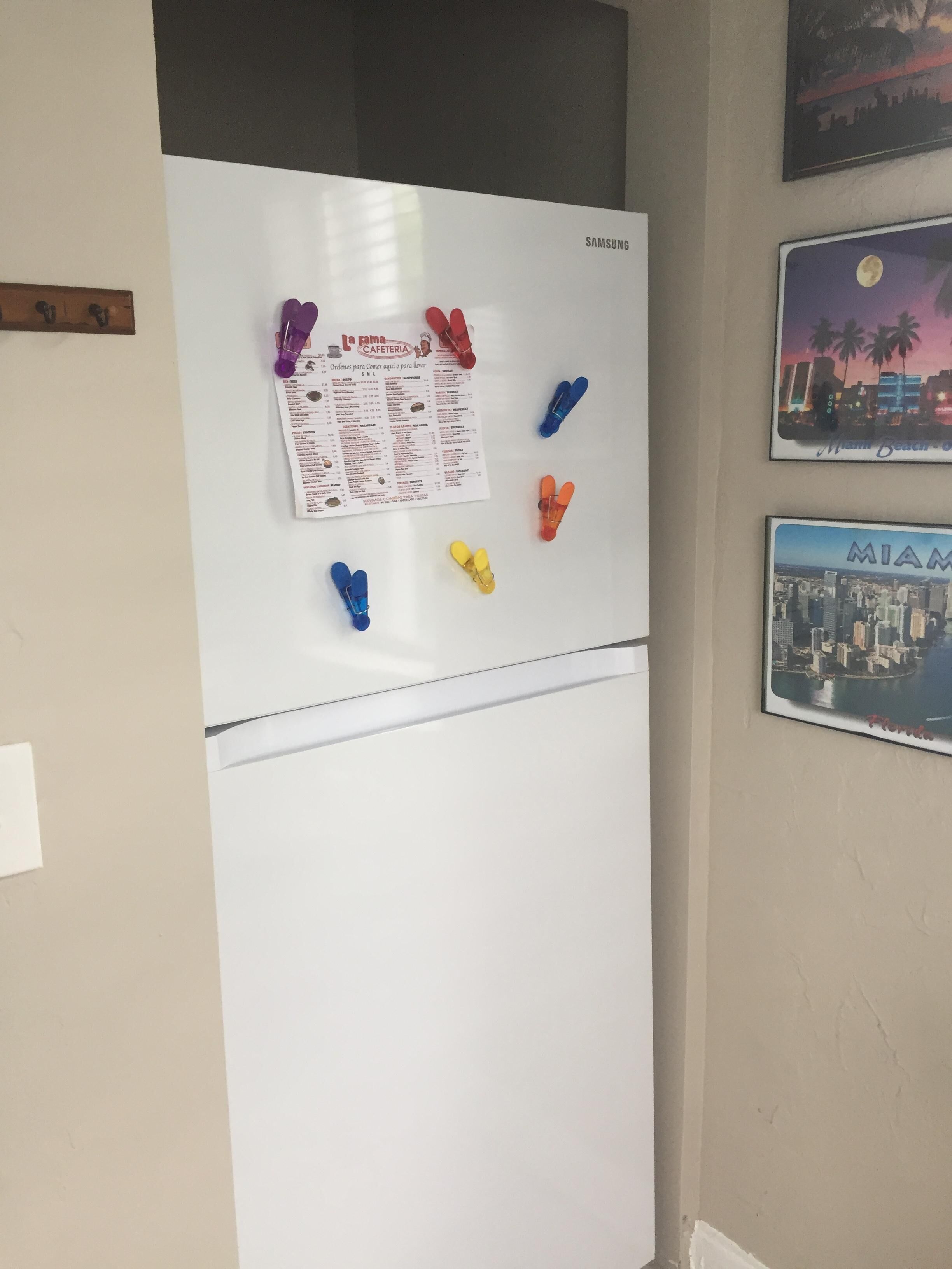 A white refrigerator with a menu and colorful clothespins on the door.
