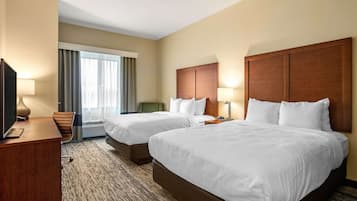 Habitación de hotel con dos camas, un escritorio, un televisor y una ventana con cortinas.
