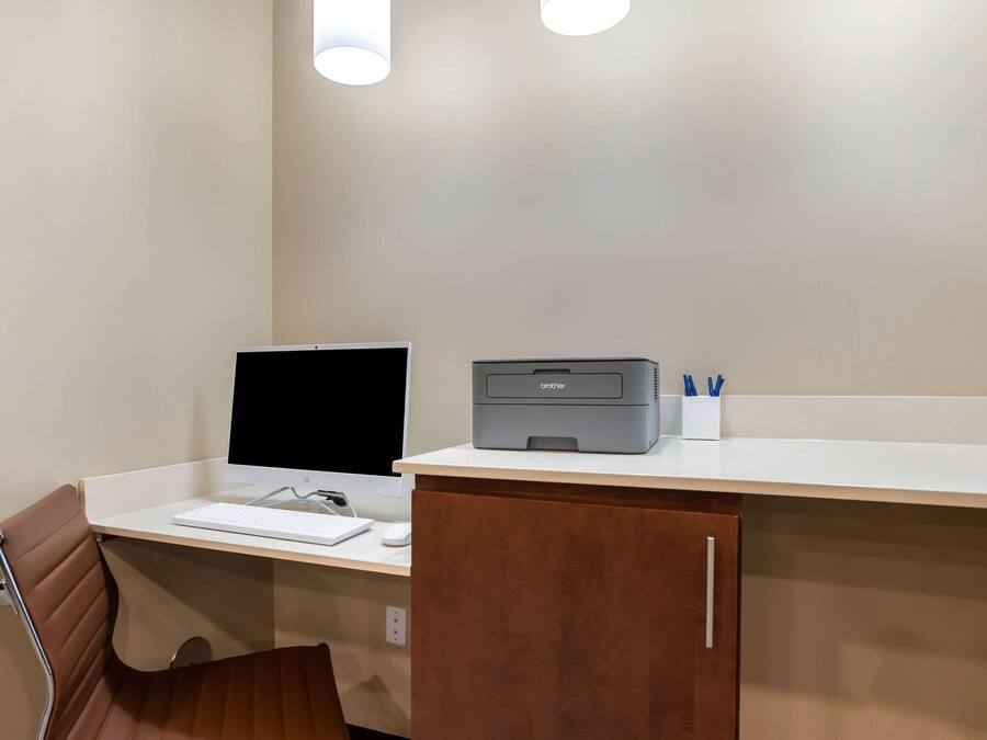Una habitación de hotel con un escritorio, una computadora e impresora.