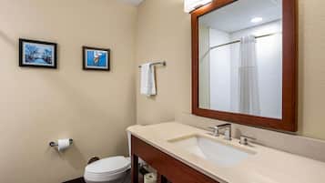 Un baño con inodoro blanco, lavamanos con espejo y dos cuadros en la pared.