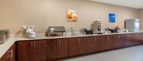 A hotel reception area with a long counter, various appliances, and a refrigerator.