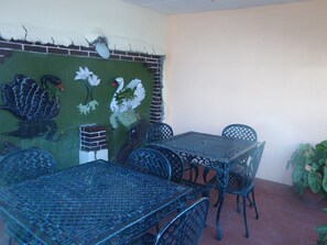 A patio with a table and chairs, a mural with swans and flowers, and a brick wall. - Hostal Luly y Rene (Cienfuegos)