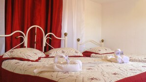 Ein Bett mit weißem Kopfteil, roten Vorhängen und einer gemusterten Bettdecke.