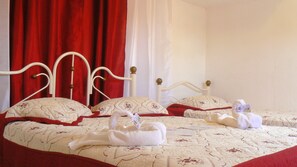 A bed with a white headboard, red curtains, and a patterned bedspread. - Hostal Luly y Rene (Cienfuegos)